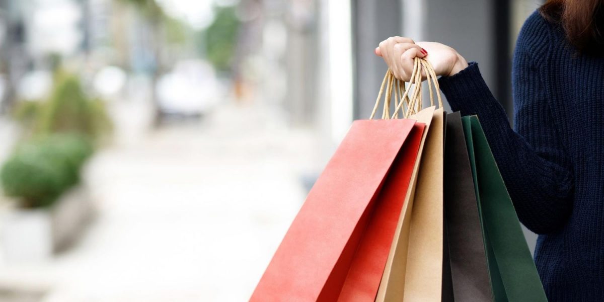 Foto detalle de una persona con unas bolsas de la compra, en referencia a consumir menos y vivir mejor.