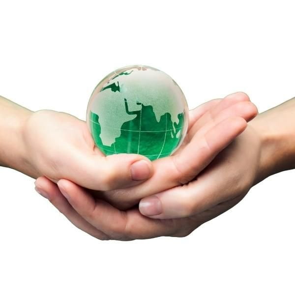 Imagen de dos manos entrelazadas sosteniendo un planeta Tierra de color verde, simbolizando la relación entre el medio ambiente y la humanidad.