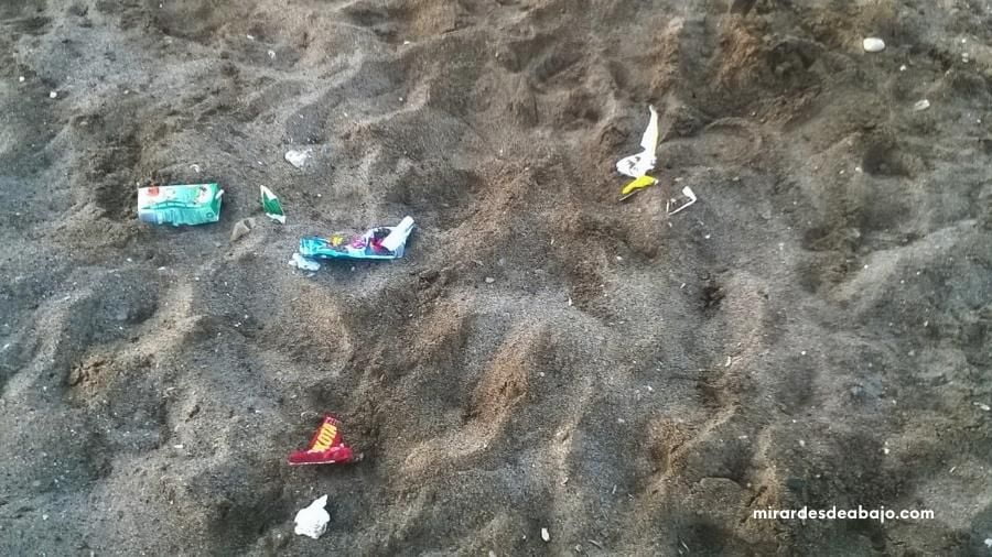 Foto con plásticos y neuroplásticos en la arena de la playa. Ejemplo de imágenes del mar contaminado.