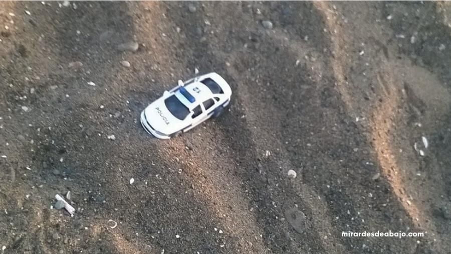 Foto de un coche de juguete como una basura más en la playa.
