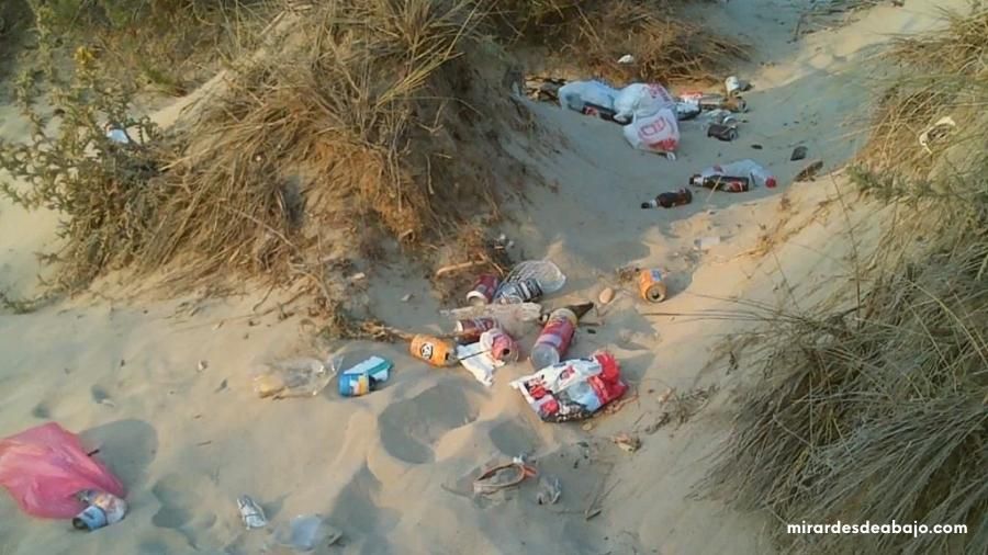 Foto de una zona de arena de la playa contaminada por basuras y plásticos. Imágenes del mar contaminado.
