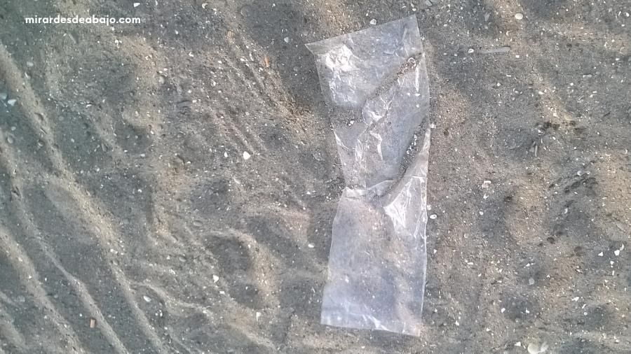 Foto de una pequeña bolsa de plásticos y microplásticos sobre la arena.