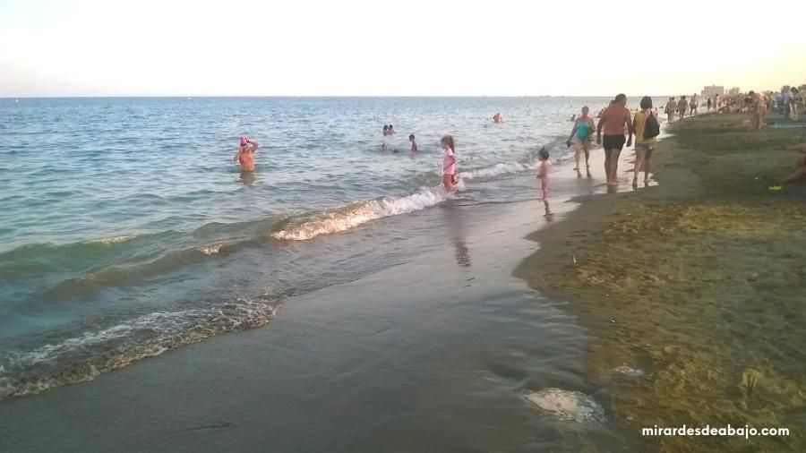 Foto de personas disfrutando de la playa junto al mar.