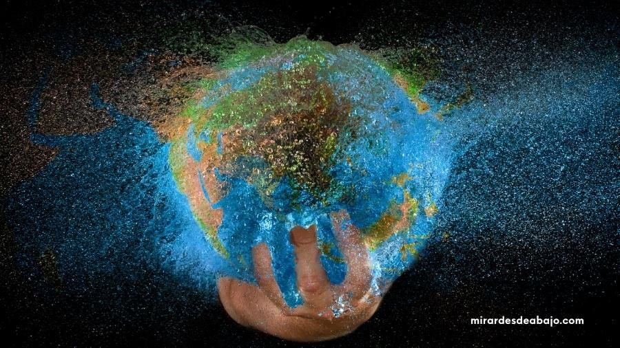 Dibujo del planeta Tierra deshaciéndose en la mano de una persona en referencia al decrecimiento económico, social y medioambiental.